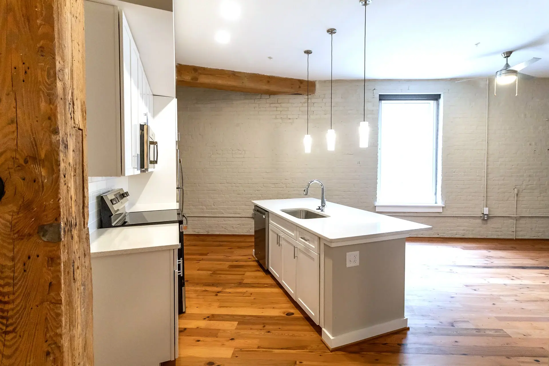 Modern, all-white kitchen with hardwood floors at The Watkins